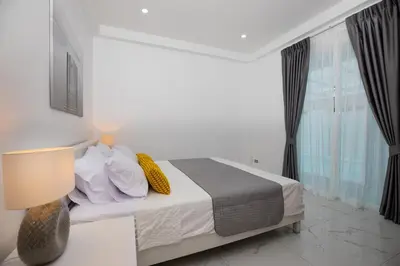 a white bedroom with a bed and a window at Villa Homey in Patong Beach