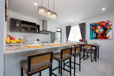 a kitchen with a bar with chairs and a table at Villa Homey in Patong Beach