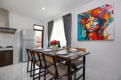 a dining room table with chairs and a painting on the wall at Villa Homey in Patong Beach