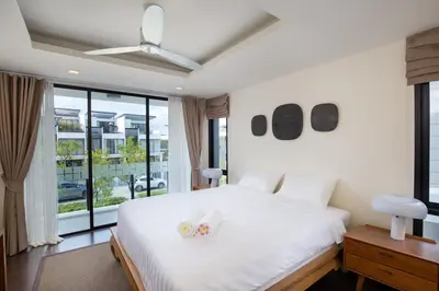a bedroom with a large white bed with two candles on it at Modern 5-Bedroom Pool Villa in Laguna Phuket