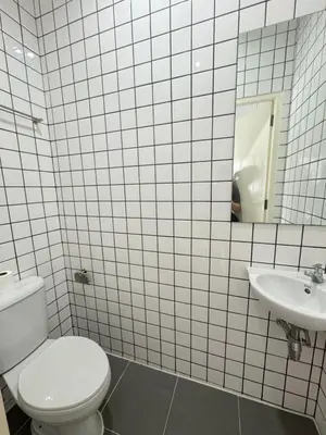 a white tiled bathroom with a toilet and a sink at \u65e5\u5f0f\u5c0f\u9547\u522b\u5885 in Phuket