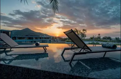 two lounge chairs sitting on a swimming pool with the sunset at C225 City Gate Kamala Great facilities 600m to beach in Kamala Beach