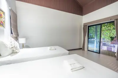 a bedroom with two beds and a large window at Pasak Villa in Laguna Phuket