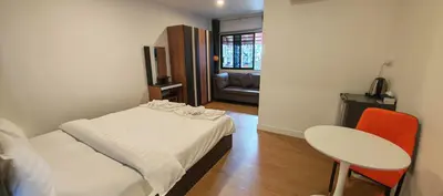 a small room with a bed and a table and a chair at Tiger Nanai guest house in Patong Beach
