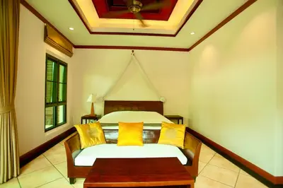 a bedroom with a bed with yellow pillows and a table at Rose Pool Villa The perfect private oasis in Rawai Beach