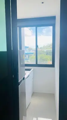 a kitchen with a large window and a white refrigerator at Utopia Central Kathu Condo in Phuket Town
