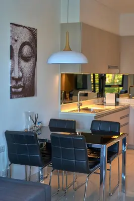 a kitchen with a table with blue chairs and a sink at Cassia Residences 1BDR Lake view in Laguna Phuket