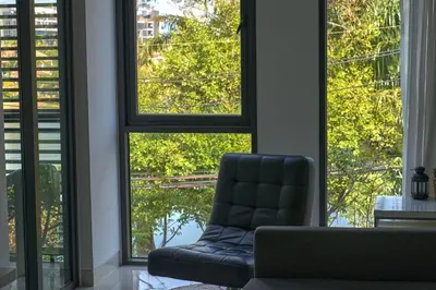 a black chair in a room with large windows at Cassia Residences 1BDR Lake view in Laguna Phuket