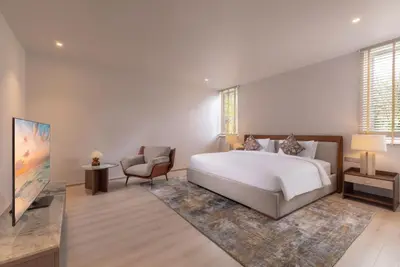 a bedroom with a large white bed and a chair at Villa AMANN in Phuket Town