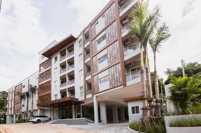 an apartment building with a palm tree in front of it at Karon rooftop pool condo in Karon Beach