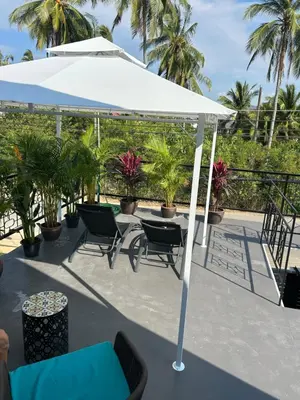 a white umbrella on a patio with chairs and plants at Rawai Beach studio in Nai Harn Beach
