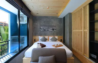 a bedroom with a bed and a chair and a window at ReLife The Windy Condo B218 Naiharn in Rawai Beach