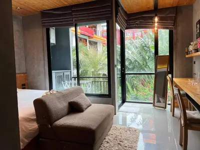 a bedroom with a bed and a chair and windows at ReLife The Windy Condo B218 Naiharn in Rawai Beach