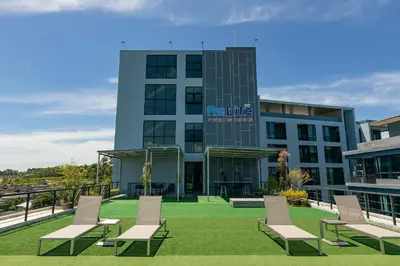 a building with chairs on the lawn in front of it at ReLife The Windy Condo B218 Naiharn in Rawai Beach