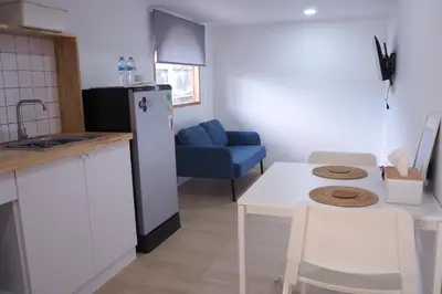 a kitchen with a refrigerator and a table with a blue chair at Cozy room Maikhao Phuket in Ban Ao Tu Khun
