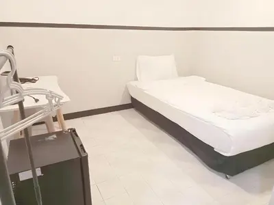 a small bed in a room with a suitcase at XX Mitr Inn Phuket Old Town -มิตร อินน์ ภูเก็ตโอลทาวน์ in Phuket Town