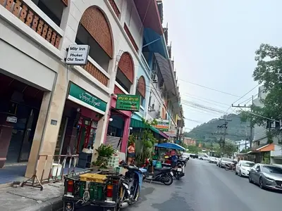 a group of people sitting on a street near a building at XX Mitr Inn Phuket Old Town -มิตร อินน์ ภูเก็ตโอลทาวน์ in Phuket Town