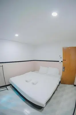 a large white bed in a room with a wooden door at XX Mitr Inn Phuket Old Town -มิตร อินน์ ภูเก็ตโอลทาวน์ in Phuket Town