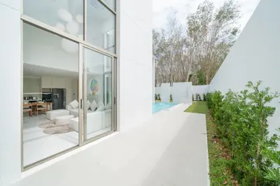 an external view of a white house with glass windows at Brand New & Modern Luxury 4BR Pool Villa in Residence Lux Pride 2 V12 in Bang Tao Beach