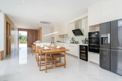 a large kitchen with a wooden table and appliances at Brand New & Modern Luxury 4BR Pool Villa in Residence Lux Pride 2 V12 in Bang Tao Beach