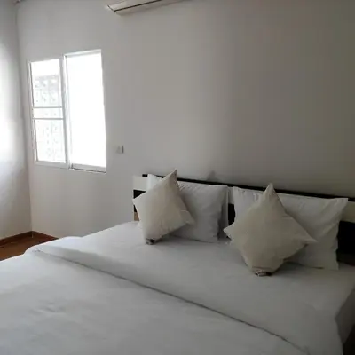 a white bed with white pillows and a window at The first house 11126 in Ban Phlu Yai