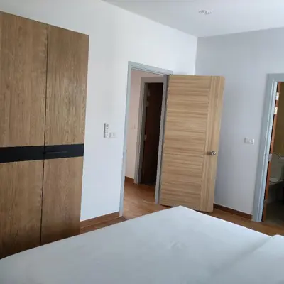 a room with a bed and two wooden cabinets at The first house 11126 in Ban Phlu Yai