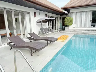 a swimming pool with two chairs and a umbrella at Villa Kirana in Rawai Beach