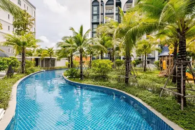a swimming pool with palm trees and buildings at The Title Halo1 2Bedroom Apartment Naiyang beach in Nai Yang Beach