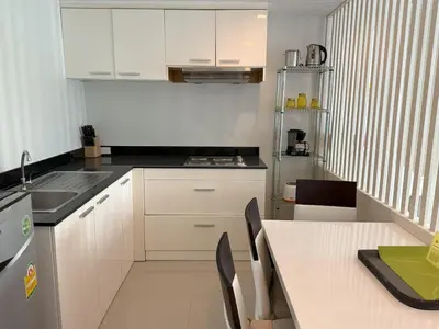 a kitchen with white cabinets and a table with chairs at Private apartment at Kris Condo by Lofty in Surin Beach