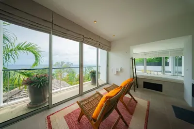 a living room with a couch and a large window at Surin Heights Villa in Surin Beach
