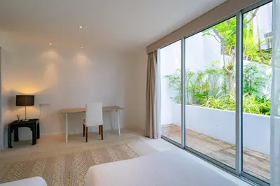 a bedroom with a desk and a large window at Surin Heights Villa in Surin Beach