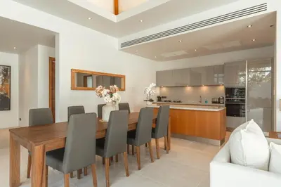 a kitchen and dining room with a wooden table and chairs at V165 Famous Anchan Flora 4 BR in Thalang