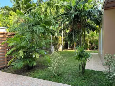 a garden with two palm trees next to a house at Nai Thon villa with pool, garden, rooftop terrace in Nai Thon Beach