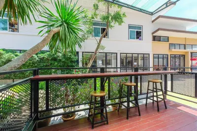a balcony with bar stools and a palm tree at The Little Nest Phuket in Phuket Town
