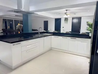 a kitchen with white cabinets and a black counter top at Peaceful Patong Penthouse in Patong Beach