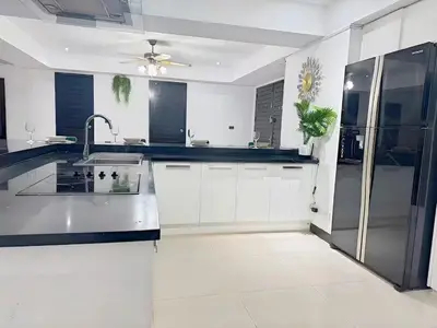 a kitchen with white cabinets and a sink and a fan at Peaceful Patong Penthouse in Patong Beach