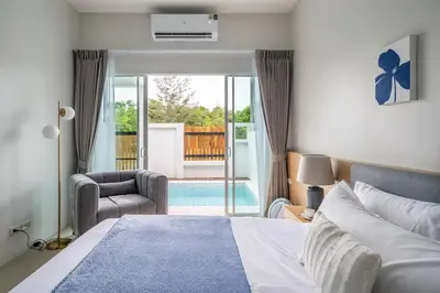 a bedroom with a bed and a chair and a balcony at Laguna Beach Villa Phuket 207byน้องมังคุด in Ban Pak Lak