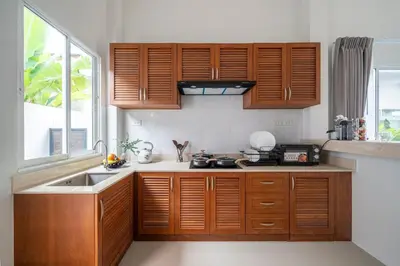a kitchen with wooden cabinets and a sink at Laguna Beach Villa Phuket 207byน้องมังคุด in Ban Pak Lak
