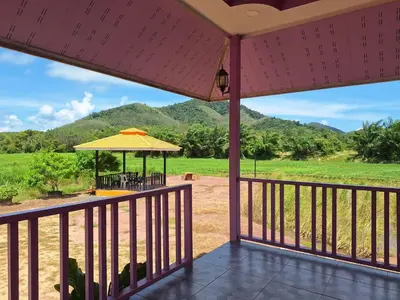 a view from the deck of a house with mountains in the background at ทุ่งนา รีสอร์ท Rice Field Resort in Ban Khiam Ngam