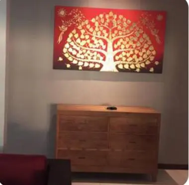 a living room with a painting of a tree on the wall at Pool Villa in Thalang in Ban Na Nai