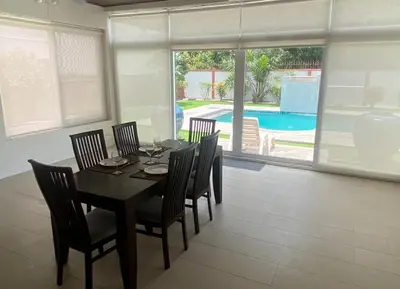 a dining room with a table and chairs and a pool at Pool Villa in Thalang in Ban Na Nai