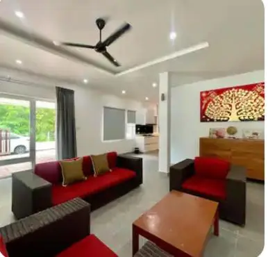 a living room with a red couch and a table at Pool Villa in Thalang in Ban Na Nai