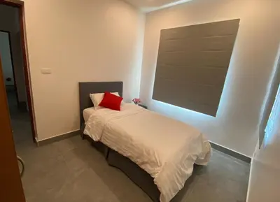 a small bedroom with a bed with a red pillow at Pool Villa in Thalang in Ban Na Nai