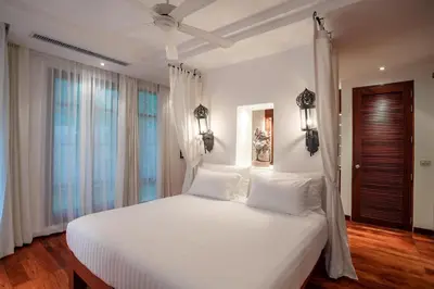 a bedroom with a large white bed with white pillows at Villa in the Park, Surin Beach, Phuket in Surin Beach