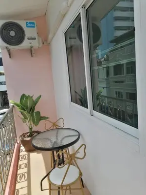 a balcony with a table and two stools and a window at Patong Beach Dream House in Patong Beach