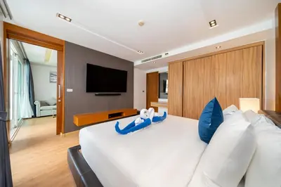 a bedroom with a large white bed with blue pillows at Spacious apartment with ocean view & jacuzzi in Patong Beach