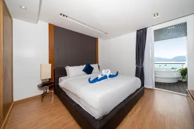 a bedroom with a large bed and a bath tub at Spacious apartment with ocean view & jacuzzi in Patong Beach
