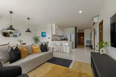 a living room with a couch and a kitchen at 3BR Suite Surin Beach Phuket - Near 2 beaches in Surin Beach