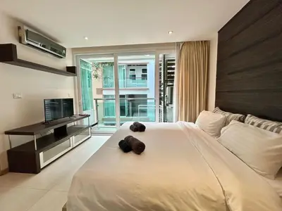 a bedroom with a large white bed and a television at 1 bedroom walk to Kalim in Patong Beach