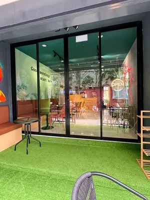 a restaurant with a large window with a table and chairs at Pupa Women Hostel in Patong Beach